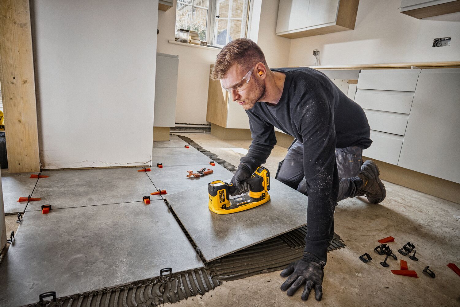 User installing tile flooring with DEWALT 20V MAX  Grabo Lifter 