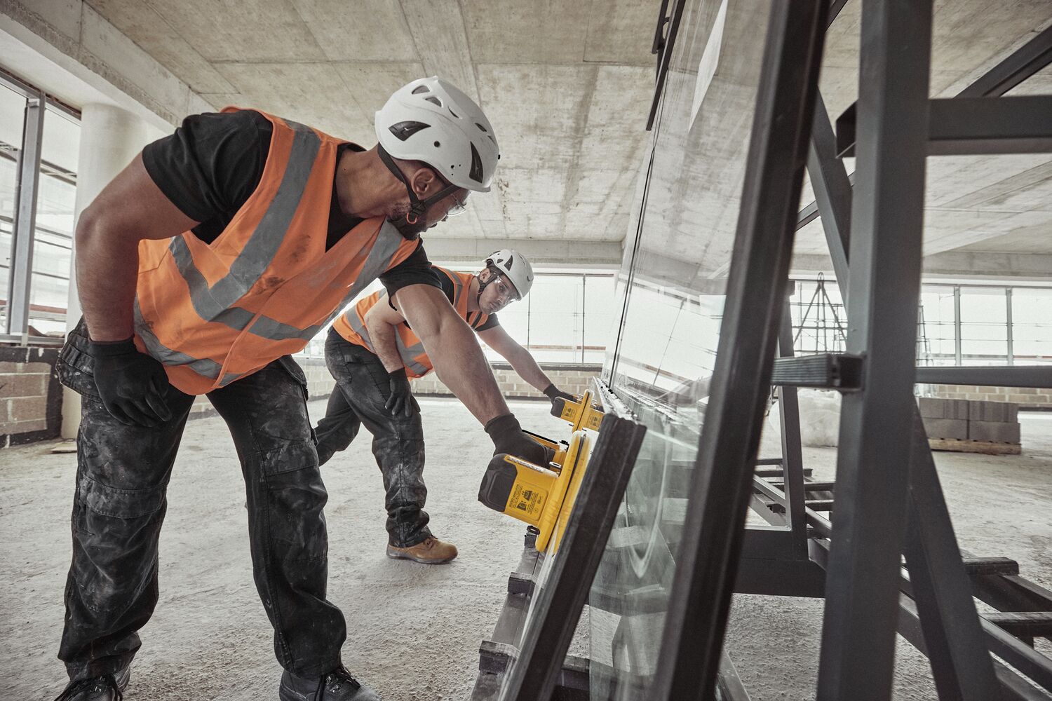 Two users lifting large glass panel with DEWALT 20V MAX Grabo Lifters