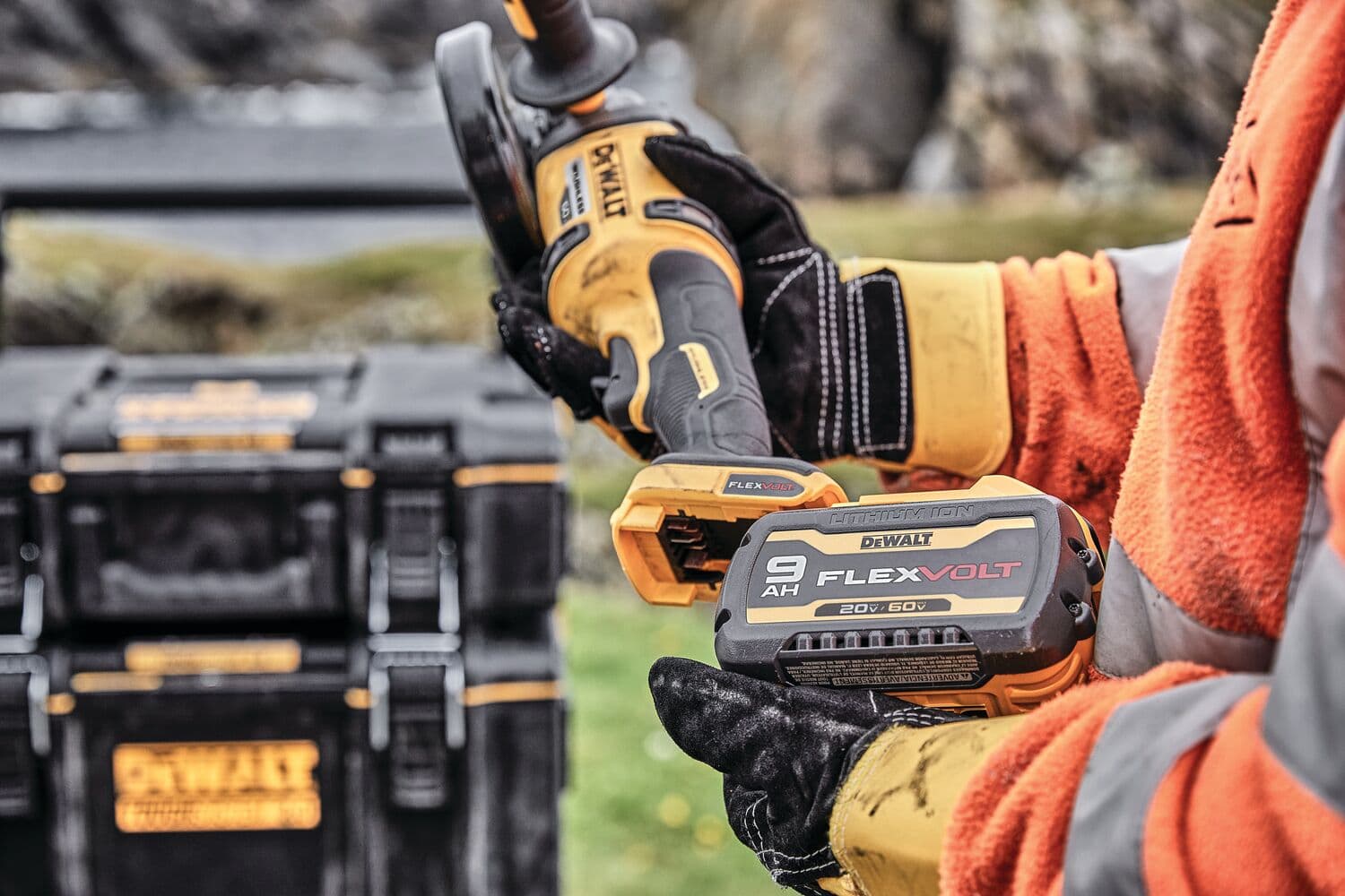 Trabajador sostiene batería DEWALT FlexVolt y herramienta afuera, cajas DEWALT visibles al fondo.
